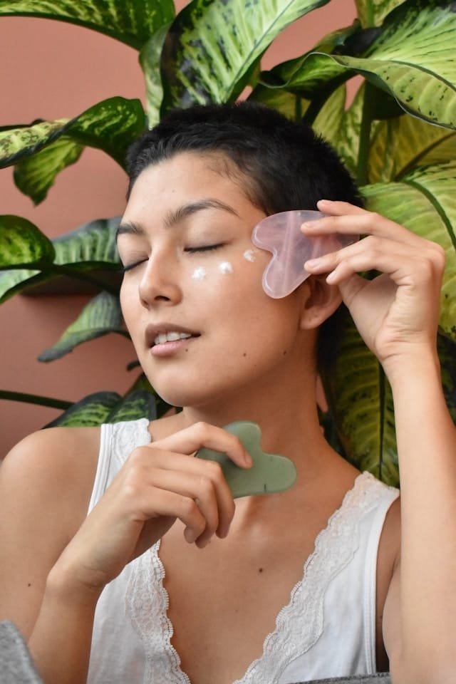 Woman holding Gua Sha stones in pink and green